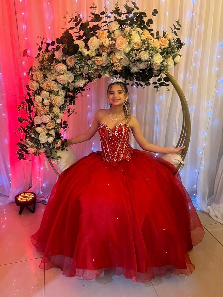 Debutante de vermelho no arco de flores