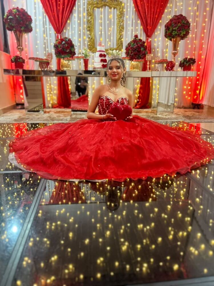 Debutante de vestido vermelho sentada na pista de LED